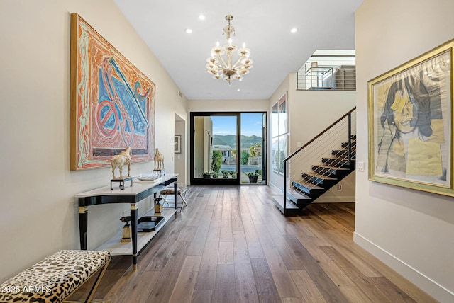 foyer with recessed lighting, wood finished floors, baseboards, stairway, and an inviting chandelier