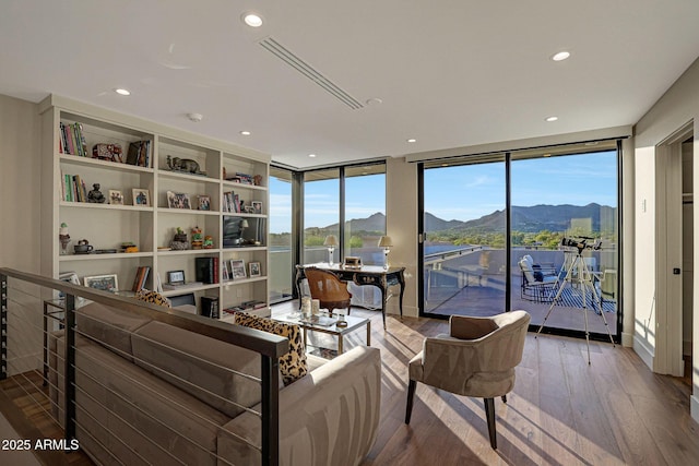 living room featuring a mountain view, expansive windows, plenty of natural light, and hardwood / wood-style flooring