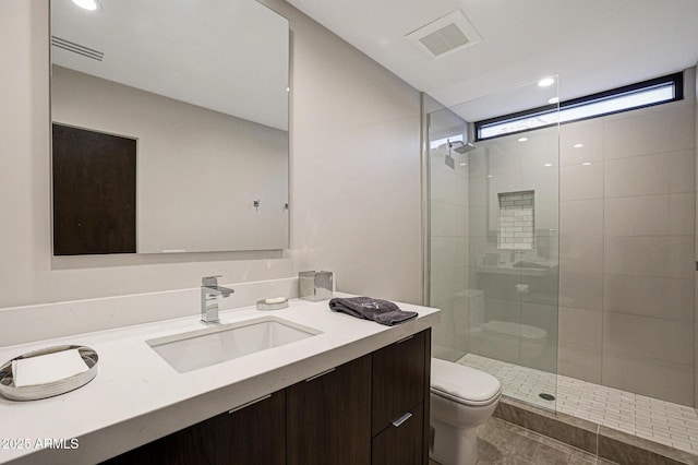 full bathroom featuring visible vents, toilet, a healthy amount of sunlight, a tile shower, and vanity