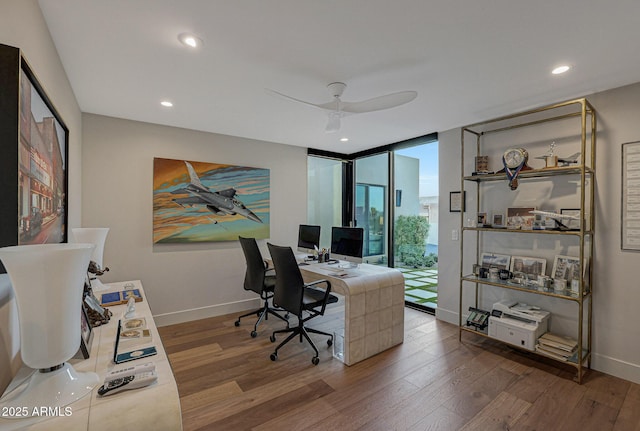 home office with recessed lighting, floor to ceiling windows, baseboards, and wood finished floors