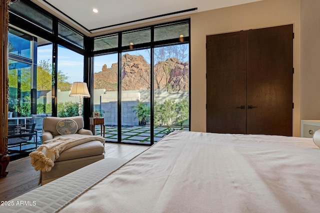 bedroom with access to outside, floor to ceiling windows, and wood finished floors