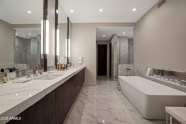 bathroom featuring marble finish floor, a freestanding tub, a sink, and a marble finish shower