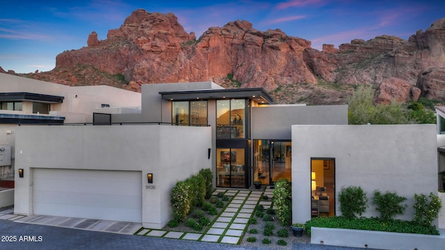 contemporary house featuring a garage, a balcony, and stucco siding