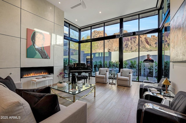 interior space with plenty of natural light, expansive windows, a fireplace, and wood finished floors