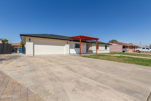 view of front of house with stucco siding, an attached garage, concrete driveway, and fence