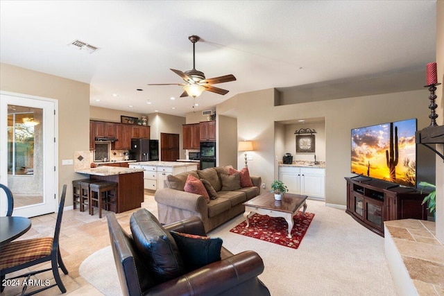 living room featuring light carpet, sink, and ceiling fan