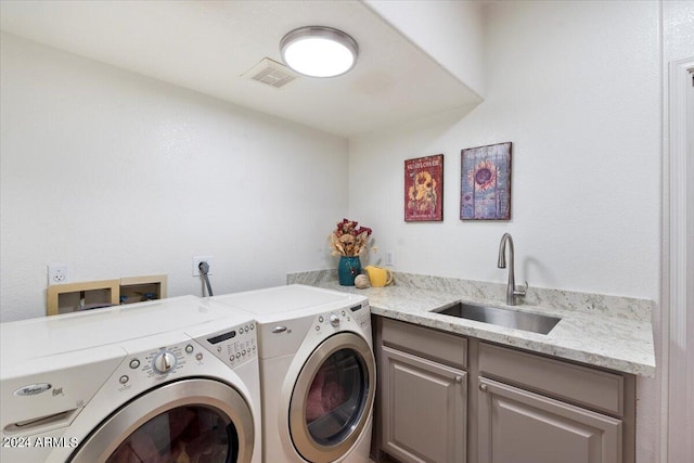 clothes washing area featuring sink, washer and dryer, and cabinets