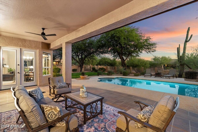 pool at dusk with a patio, an outdoor hangout area, and ceiling fan