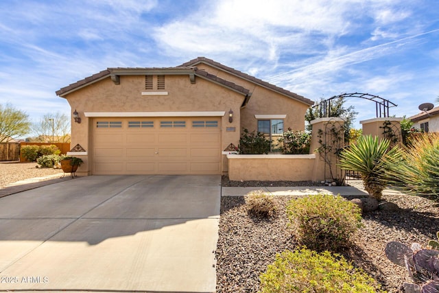 view of front facade with concrete driveway, a tiled roof, an attached garage, fence, and stucco siding