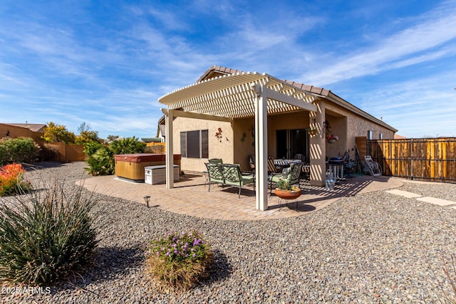 back of property featuring a pergola, a patio area, stucco siding, and a hot tub