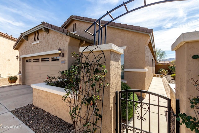 view of front of home featuring a garage, driveway, fence, and stucco siding