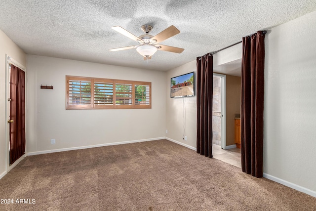 spare room with light carpet, ceiling fan, and a textured ceiling