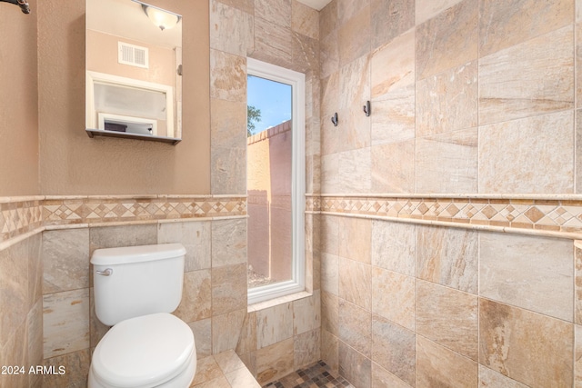 bathroom featuring toilet and tile walls