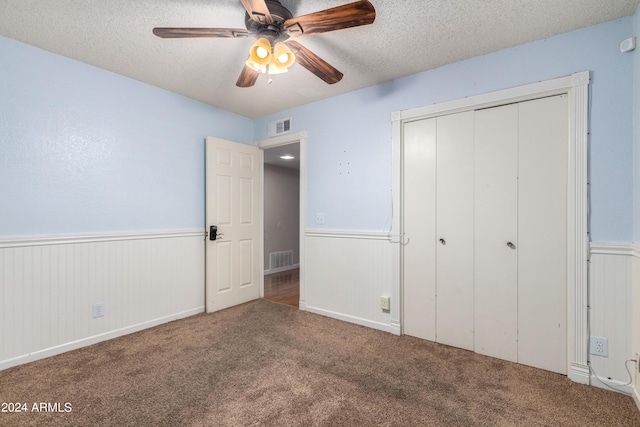 unfurnished bedroom featuring carpet flooring, a textured ceiling, a closet, and ceiling fan