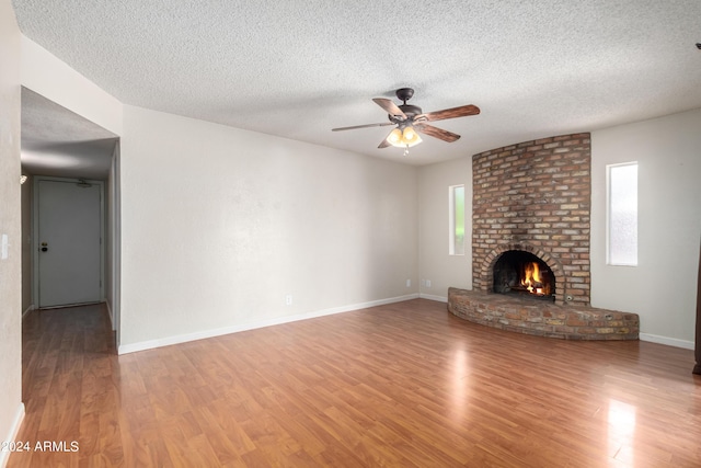 unfurnished living room featuring a fireplace, hardwood / wood-style floors, a textured ceiling, and ceiling fan