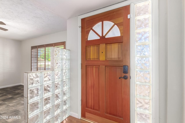 foyer with ceiling fan and a textured ceiling