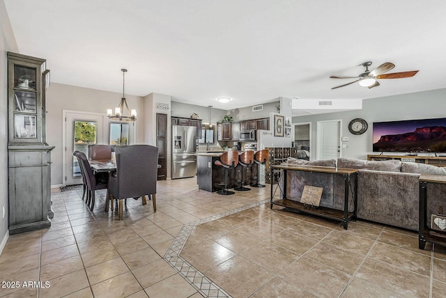 living room featuring light tile patterned flooring and ceiling fan with notable chandelier