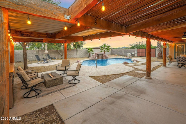 pool at dusk featuring pool water feature, an outdoor fire pit, and a patio