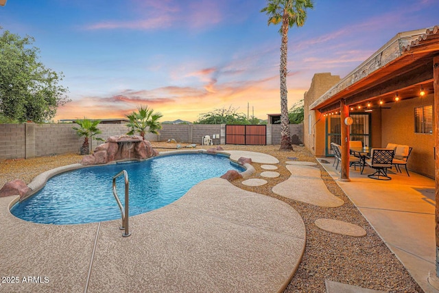 pool at dusk featuring pool water feature and a patio