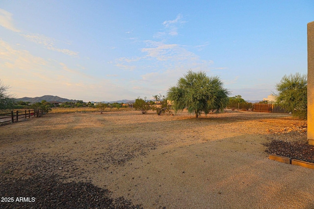 yard at dusk featuring a rural view and a mountain view