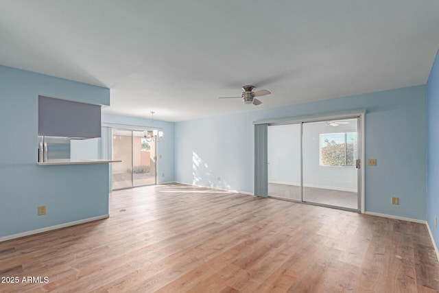 unfurnished living room featuring light wood-type flooring and ceiling fan with notable chandelier