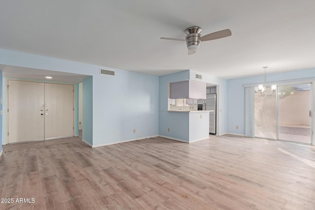 unfurnished living room featuring ceiling fan with notable chandelier and light hardwood / wood-style floors