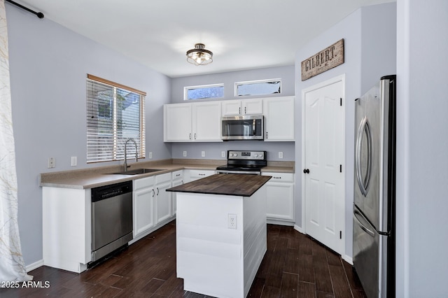 kitchen featuring wooden counters, a center island, dark wood-style floors, stainless steel appliances, and a sink