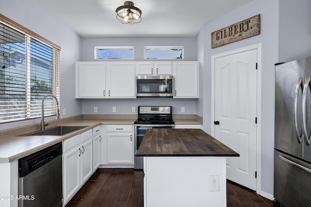 kitchen featuring dark wood-style floors, a sink, stainless steel appliances, wood counters, and white cabinetry