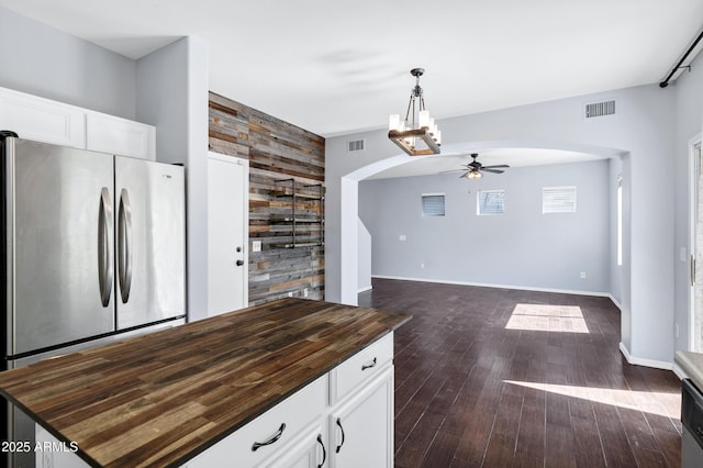 kitchen with visible vents, arched walkways, butcher block counters, and freestanding refrigerator