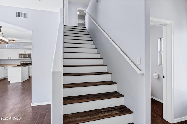 stairway featuring visible vents, baseboards, and wood finished floors