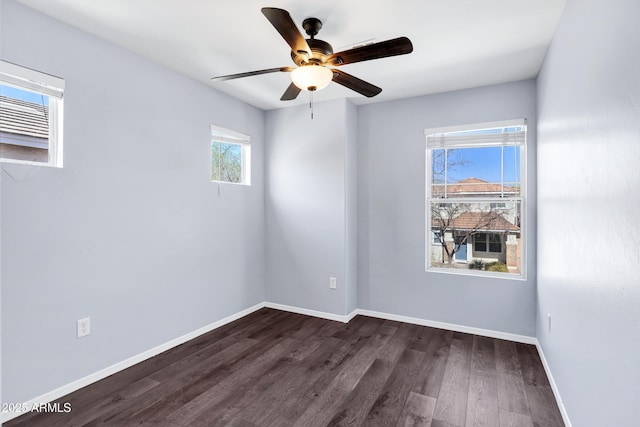 unfurnished room featuring baseboards, dark wood-type flooring, and a ceiling fan