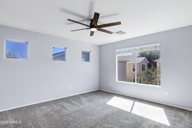 carpeted spare room featuring visible vents, baseboards, and ceiling fan