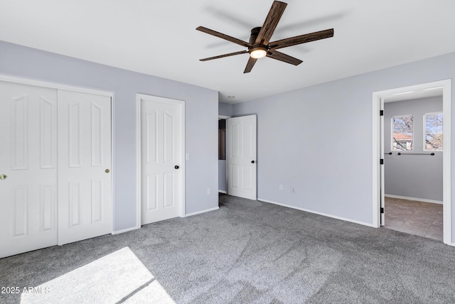 unfurnished bedroom with a ceiling fan, baseboards, ensuite bath, multiple closets, and carpet flooring