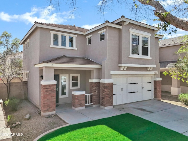 view of front of home with stucco siding, brick siding, an attached garage, and driveway