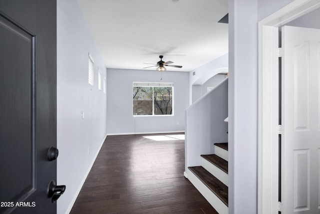 interior space featuring baseboards, stairs, a ceiling fan, and dark wood-style flooring