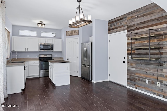 kitchen with a sink, dark wood-type flooring, appliances with stainless steel finishes, white cabinetry, and a center island