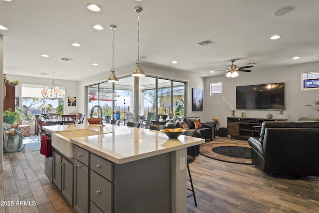 kitchen featuring open floor plan, light countertops, a center island with sink, and visible vents