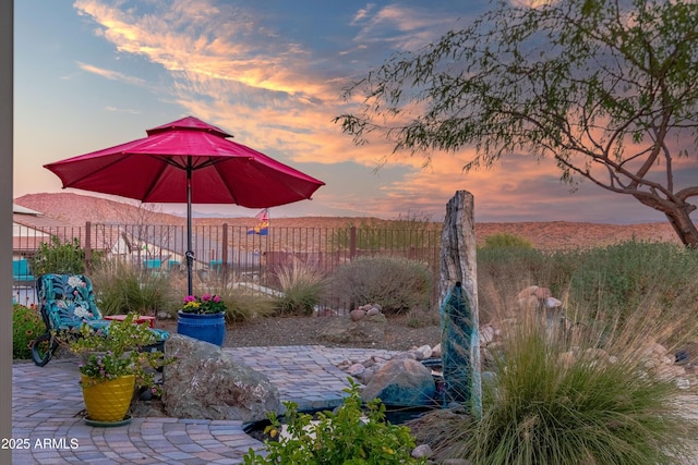 patio terrace at dusk featuring fence