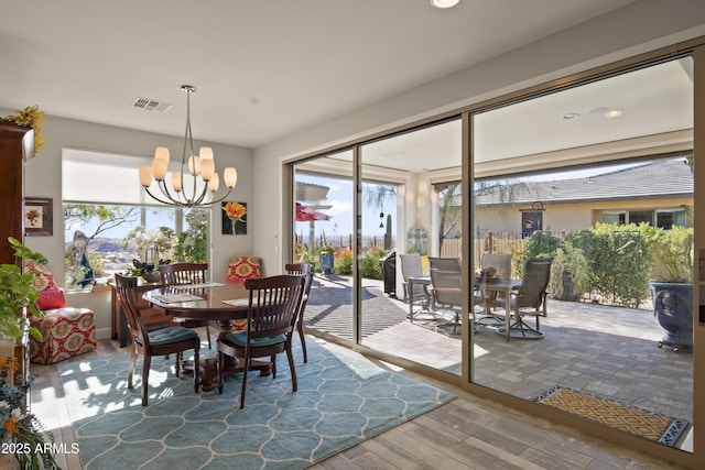 dining space with a wood stove, visible vents, a wealth of natural light, and wood finished floors