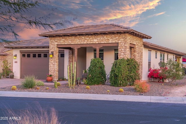 view of front of house with stone siding, an attached garage, and stucco siding