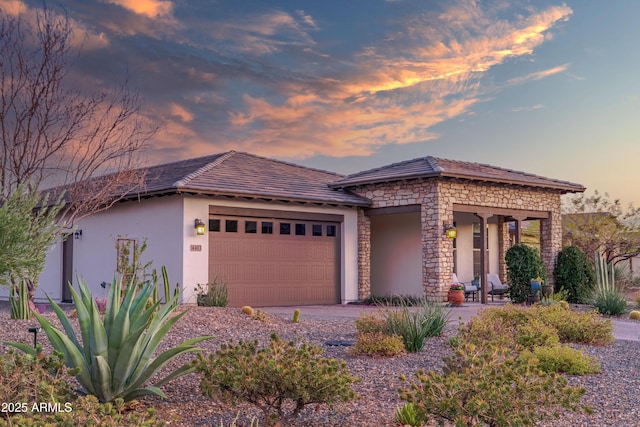 view of front of house featuring stone siding, an attached garage, and stucco siding