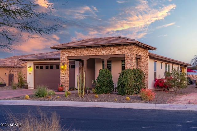 view of front of house with a garage, stone siding, driveway, and stucco siding