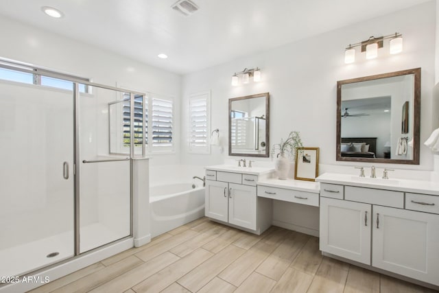 bathroom with ceiling fan, vanity, and shower with separate bathtub