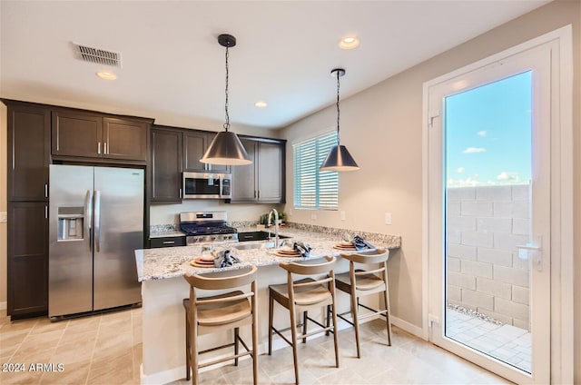 kitchen with light stone counters, visible vents, a peninsula, a sink, and stainless steel appliances