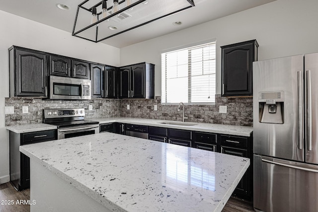 15365 W Valentine St, Surprise, AZ 85379 - kitchen with stainless steel appliances, a sink, light stone counters, decorative backsplash, and recessed lighting