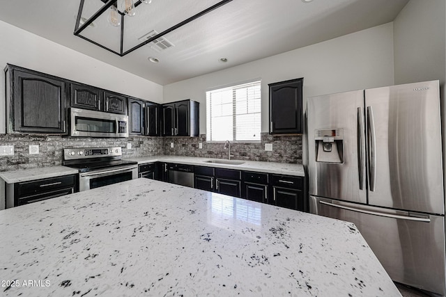 15365 W Valentine St, Surprise, AZ 85379 - kitchen featuring appliances with stainless steel finishes, a sink, light stone counters, backsplash, and dark cabinetry