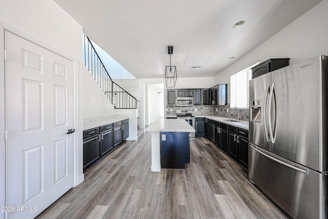 15365 W Valentine St, Surprise, AZ 85379 - kitchen with stainless steel appliances, a sink, a center island, dark wood finished floors, and decorative backsplash
