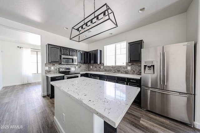 15365 W Valentine St, Surprise, AZ 85379 - kitchen with appliances with stainless steel finishes, a kitchen island, backsplash, dark wood finished floors, and recessed lighting