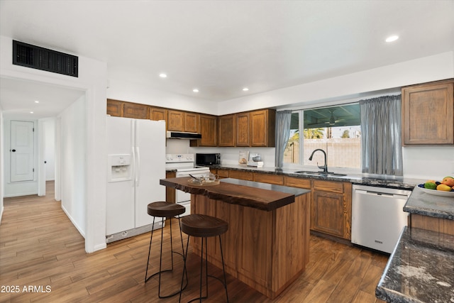 kitchen featuring sink, white appliances, a kitchen breakfast bar, dark hardwood / wood-style floors, and a kitchen island