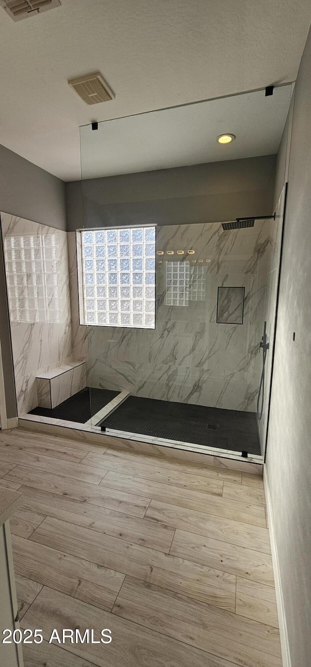 bathroom with tiled shower and hardwood / wood-style floors